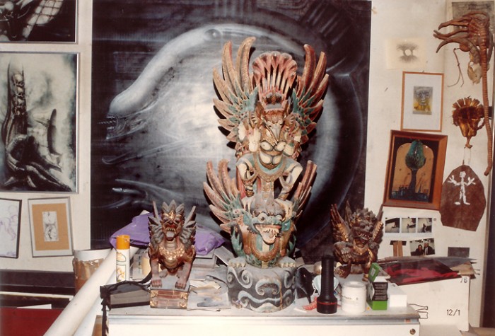Holzgeschnitzte Dämonenfiguren, Totems, Fetische und mit Bildern überfrachtete Wände dominieren in der gesamten Behausung. Rechts ein Originalmodell des Face-Huggers aus Alien I.